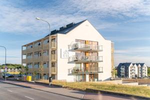 a white building on the side of a street at Sunday Resort Ustronie Morskie in Ustronie Morskie