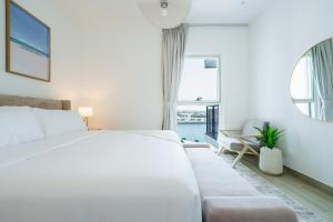 a white bedroom with a bed and a couch at One Bedroom Apartment by Otolo Homes with Free Yas Theme Park Tickets in Abu Dhabi +74 photos