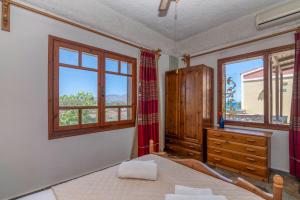 a bedroom with a bed and a dresser and windows at Drapanias BeachFront Apartments - Marinakis in Kissamos +55 photos
