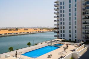 a swimming pool next to a building and a river at One Bedroom Apartment by Otolo Homes with Free Yas Theme Park Tickets in Abu Dhabi