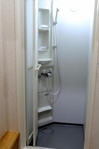 a shower in a bathroom with a door open at Ocho Guest House in Sapporo