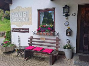 eine Bank vor einem Gebäude mit rosa Kissen darauf in der Unterkunft Ferienwohnung Karlsruh in Warmensteinach