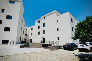 a white building with a car parked in front of it at Aren 1 in Vlorë