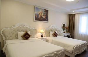 two beds in a hotel room with white sheets at Tuyet Son Hotel (TS Ocean Hotel) in Da Nang