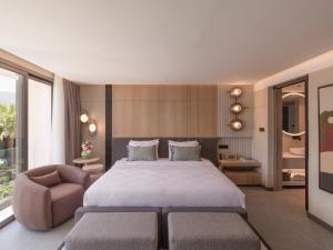 a bedroom with a large bed and a chair at kolektif suites in Kyrenia