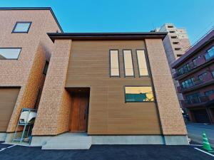 una casa de ladrillo con puerta de madera en una calle en 新屋 札幌市中心 近圓山公園 挑高設計客廳 4房 2廁所 1浴室 1淋浴 最大10人 可停車, en Sapporo