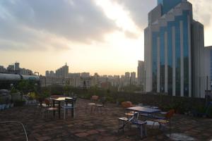 a patio with tables and chairs and a city skyline at Notting Hill Hostel in Bao'an