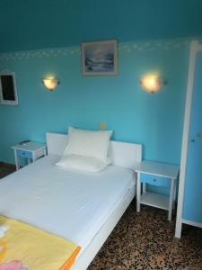 a bedroom with a white bed and two tables at Magdalini in Votsi