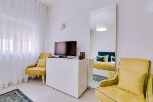 a living room with two chairs and a tv at Apartamentos Sol & Ria in Olhão