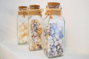 drei Glasflaschen gefüllt mit verschiedenen Arten von Muscheln in der Unterkunft Maison CALAIS centre ville L in Calais
