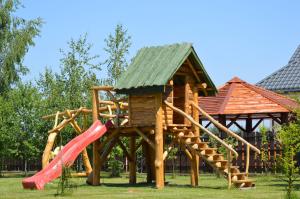a wooden playground with a slide and a house at Zacisze in Rozalin