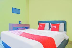 バンダールランプンにあるDancenter Divka Residenceの赤い枕が2つ付いたベッドのある寝室