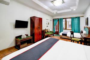 Una habitación de hotel con una cama y un televisor. en Dancenter The Ethnic Hotel, en Bandung