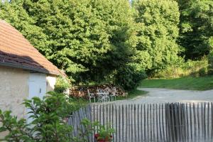 a garden with a table and a fence and trees at Maison des hôtes in Campagne