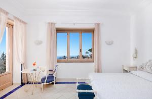 a bedroom with a bed and a table and a window at Boutique Hotel Casa Mariantonia in Anacapri