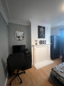 Habitación con escritorio, silla y chimenea. en room near Luton center, en Luton