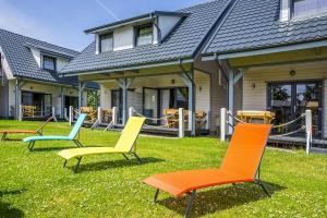 a group of chairs sitting in the grass in front of a house at Domki letniskowe Marengo in Lubiatowo