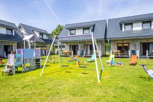 a yard with playground equipment in front of a house at Domki letniskowe Marengo in Lubiatowo