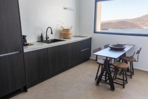 a kitchen with a sink and a table with chairs at Amazē Mykonos in Mikonos