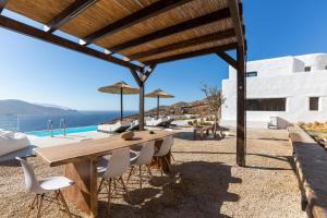 a wooden table and chairs under a pergola at Amazē Mykonos in Mikonos