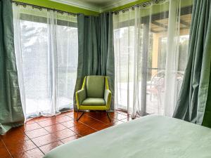a bedroom with a chair in front of a window at VIVA Quinta I Quinta do Ananás Pineapple Farmhouse in São Roque