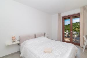 a white bedroom with a bed and a balcony at Casa Medici- Aglientu in Aglientu