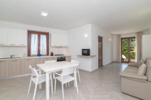 a kitchen and living room with a white table and chairs at Casa Medici- Aglientu in Aglientu