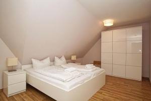 ein weißes Bett mit weißer Bettwäsche und Kissen in einem Zimmer in der Unterkunft strandnah mit Balkon, gratis Nutzung vom AHOI Erlebnisbad und Sauna in Sellin - Strandhaus Mönchgut FeWo21 in Lobbe + 20 Fotos