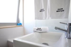 a bathroom with a white sink and a towel at Hotel Mar Bravo in Nazaré
