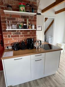a kitchen with white cabinets and a brick wall at Guesthouse Anderten in Hannover +25 photos