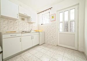 a kitchen with white cabinets and a door at Apartments and Rooms Lanča in Rab