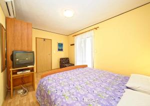 a bedroom with a purple bed and a tv at Apartments and Rooms Lanča in Rab