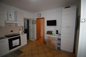 a kitchen with white cabinets and a tv on the wall at Villa MEMA in Bisceglie