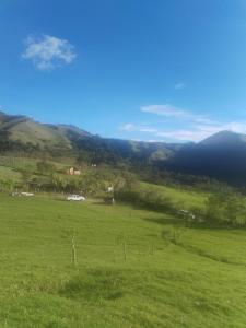 a field of green grass with mountains in the background at Las Bromelias in Coconuco