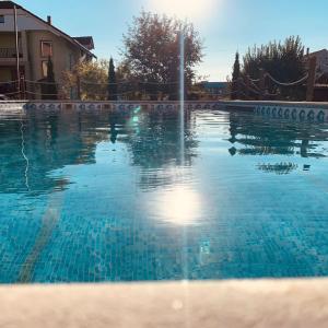 une piscine avec de l'eau bleue devant une maison dans l'établissement Free Parking Pension, à Oradea