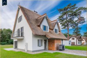 a large white house with a thatched roof at Fischerdorf DDH Hafftraum in Zirchow