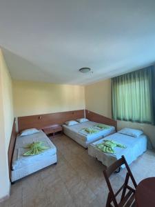a room with three beds and a table and chairs at Семеен хотел САМИ in Kranevo