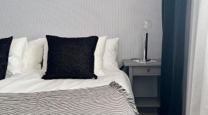 a bed with a black pillow and a table with a lamp at Hotell Norra Tullen tidigare Adas Hotell in Östhammar
