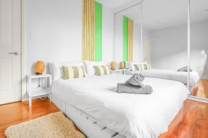 a large white bed in a room with a mirror at 2-Bedroom House Hoolloomooloo Good for 6 Guests in Sydney