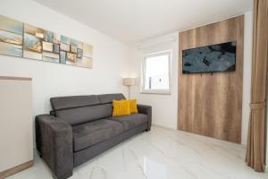 a living room with a black couch and a window at Poolside Hideout Apartments in Novalja