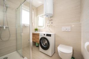 a bathroom with a washing machine and a toilet at Poolside Hideout Apartments in Novalja