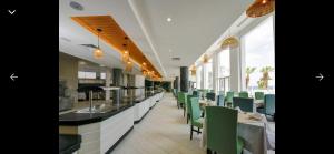 a restaurant with green chairs and a long counter at Blue Bay Appart hôtel in Monastir