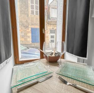 a table with two plates and glasses and a window at Studio à Montluçon in Montluçon +35 photos