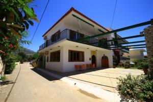 a white house with a balcony on a street at Maistreli Hotel Apartments in Stoupa