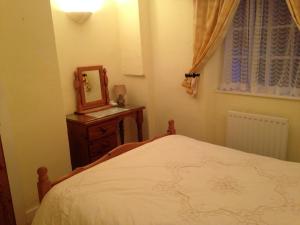 a bedroom with a bed and a mirror on a dresser at Traditional 2 Bedroom Thatched Cottage in East Budleigh