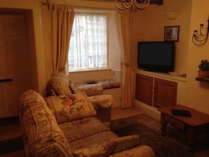 a living room with a couch and a television at Traditional 2 Bedroom Thatched Cottage in East Budleigh