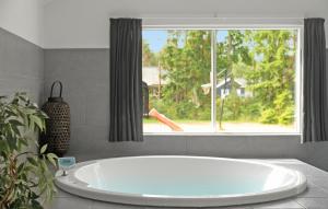 a large white tub in a bathroom with a window at Holiday Home Frederiksværk - 01 in Melby