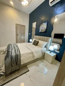 a bedroom with a large bed and a blue wall at EliteunseenSuites - 5 Bedroom Beautiful Detached House - Private Parking in Lekki