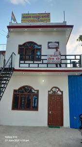 a man standing on the balcony of a building with two doors at Shri Satyanarayan ji homestay in Ayodhya
