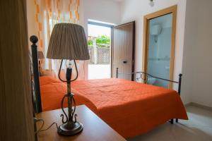 a bedroom with a orange bed with a lamp at Grappolo B&B affittacamere in Ascea